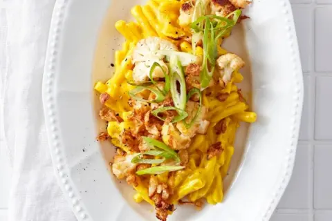 Cremiges Blumenkohl Mac and Cheese mit knusprigen Zwiebeln und Frühlingszwiebeln garniert.