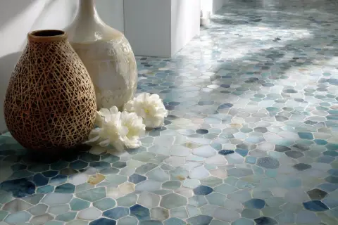 Un sol en pose mosaïque aux tons aquatiques, orné de deux vases et de fleurs blanches.
