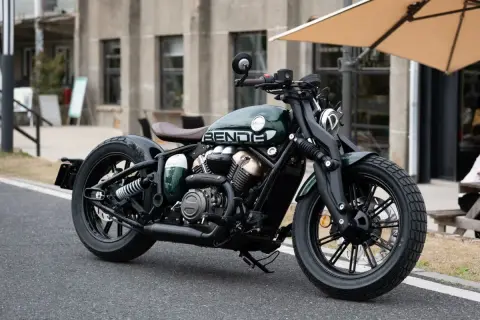 Zielony, stylowy chopper Benda, najmocniejszy chopper 125, z brązowym siedzeniem i czarnymi felgami, zaparkowany na ulicy.