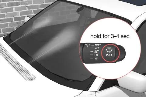Le levier de commande des essuie-glaces de voiture montre le symbole "PULL" pour activer le lave-glace.