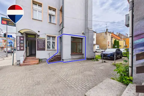 Budynek z wejściem do biura ubezpieczeń i oknem, zaznaczony niebieską ramką.