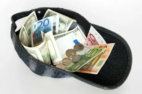 Dolarów i euro w czapce, jakby to był cały majątek z zagranicznego konta bankowego.