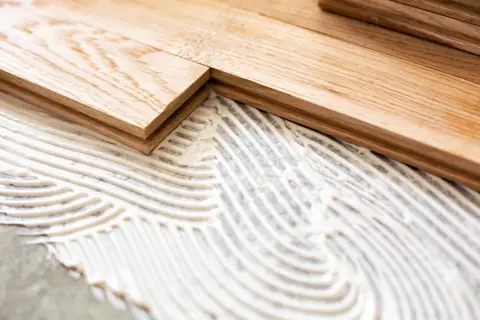 Pose de parquet en bois sur du béton avec de la colle. Les lames de bois sont prêtes à être fixées.