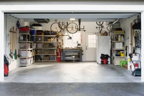 Organizzazione garage con scaffalature, biciclette appese e attrezzi. Ottime idee garage fai da te per uno spazio funzionale.