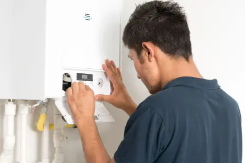 Tecnico controlla la caldaia che non carica acqua, regolando i comandi sul pannello.