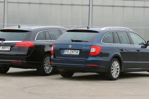 Dwa rodzinne kombi: czarny Opel Insignia i granatowa Skoda Superb stoją obok siebie.
