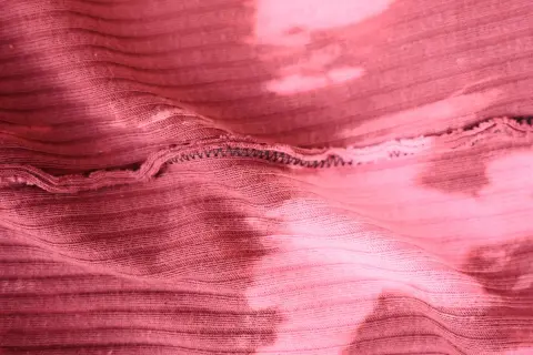 Różowa, prążkowana dzianina z efektem tie-dye. Elastyczna przędza do produkcji dzianin, widoczne szwy.