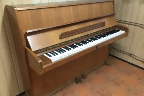 Drewniane pianino pionowe z klawiaturą. Zastanawiasz się, ile waży pianino? To instrument, który wymaga siły do przeniesienia.