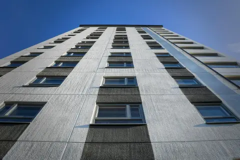 Facciata di un palazzo con file di finestre, sotto un cielo blu. Potrebbe rappresentare il punteggio minimo per casa popolare.
