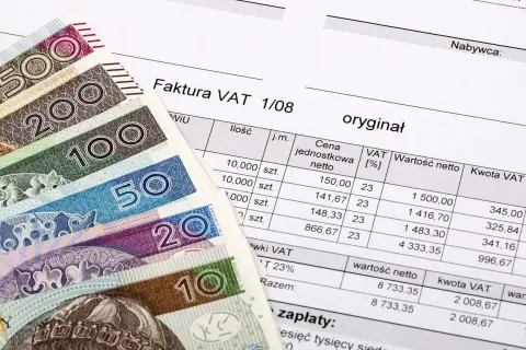 Polskie banknoty i faktura VAT. Dokument finansowy z wyszczególnionymi kwotami netto i VAT.
