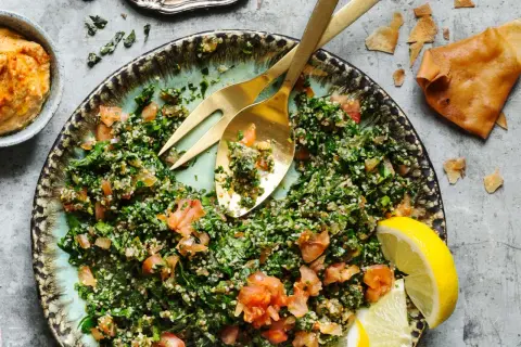 En fräsch tabbouleh med persilja, tomat och bulgur, serverad med citronklyftor och pitabröd. Ett perfekt tabbouleh recept för sommaren.