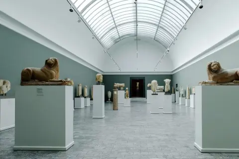 Ancient sculptures, including lion statues, are displayed in a grand hall, showcasing the impressive collection of Copenhagen art galleries.