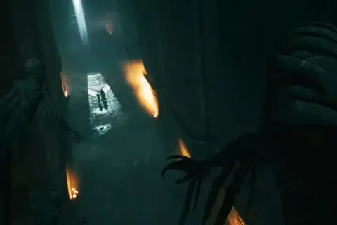 Dunkler Korridor in Hogwarts Legacy, der an Askaban erinnert. Mumienartige Gestalten lauern im Schatten, während zwei Figuren im Lichtschein voranschreiten.