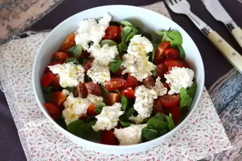 En härlig sallad med tomater, gröna blad och krämig burrata. Perfekt för ett enkelt burrata recept.