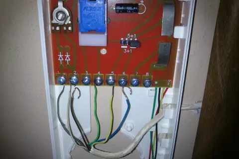 Schemat podłączenia domofonu 2 żyłowego: przewody podłączone do zacisków 1-8. Widoczne elementy elektroniczne na płytce.