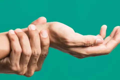 Mano che si tiene il polso, indicando dolore o fastidio, forse legato all'artrite polso.