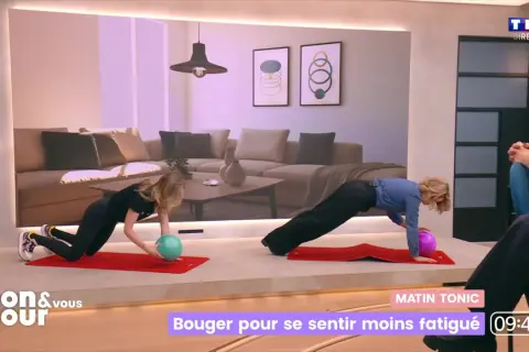 Deux femmes font des exercices sur des tapis rouges. L'une d'elles tient un ballon vert, l'autre un ballon violet. Elles semblent faire du sport tous les jours pour rester en forme.