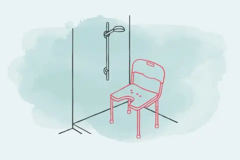 Ein roter Duschstuhl mit Aussparung steht in einer Dusche neben einer Duschstange. Ein Duschstuhl auf Rezept für mehr Sicherheit.