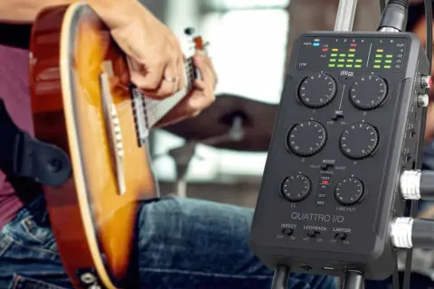Musiker spielt Gitarre, während ein iRig Quattro I/O bereitsteht, um die Musik aufzunehmen.