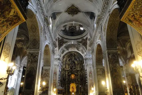 Interior de la iglesia de la Magdalena, con bóvedas ornamentadas, arcos y un retablo dorado.