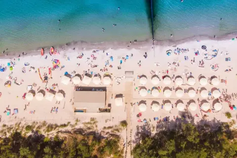 Idealne miejsce na wakacje: plaża z parasolami i ludźmi, idealna dla szukających najlepszych hoteli nad morzem z pełnym wyżywieniem.