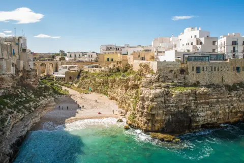 Un'idea per il tuo itinerario Puglia 7 giorni in macchina: la costa rocciosa di Polignano a Mare con la sua spiaggia e le case bianche a picco sul mare.