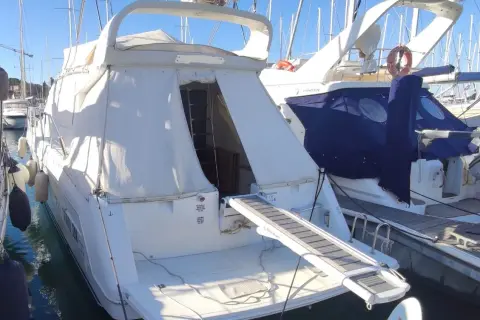 Il Raffaelli Typhoon, un lussuoso yacht bianco, è ormeggiato in un porto. La passerella è estesa, pronta per l'imbarco.
