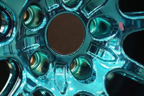 Glänzende Felgen, frisch lackiert in einem auffälligen Türkis. Die Spiegelung des Lichts auf der glatten Oberfläche lässt die Felgen fast lebendig wirken.