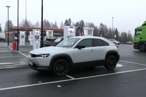 Biała Mazda MX-30 na ładowarce Ionity. Zasięg tego elektryka pozwala na spokojne podróże. Obok stacji Circle K.