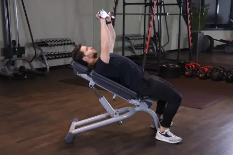 Mężczyzna wykonuje ćwiczenie incline dumbbell press na ławce skośnej, podnosząc ciężarki nad klatkę piersiową.