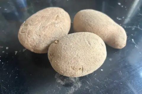 Trzy ziemniaki na czarnym tle. Czy ziemniaki mają gluten? Nie, są naturalnie bezglutenowe.