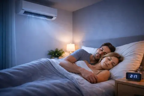 Couple dormant paisiblement sous la climatisation. La question "a combien mettre la clim dans une chambre" est résolue pour un sommeil parfait.