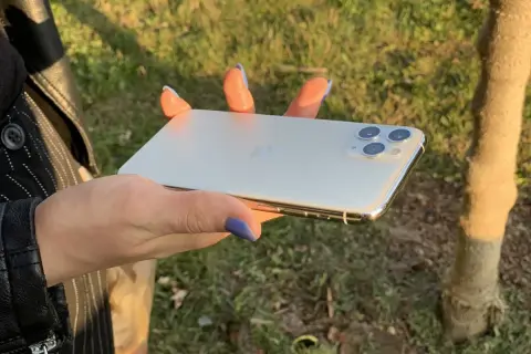 Dłoń trzyma biały iPhone 11. Wymiary telefonu idealnie pasują do dłoni, co widać na zdjęciu.