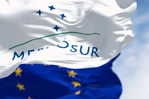 Flaga Mercosur, symbol współpracy gospodarczej, powiewa na tle błękitnego nieba.