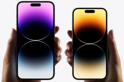 Dwie dłonie trzymają telefony iPhone 16. Jeden z nich ma fioletowy ekran, drugi złoty.