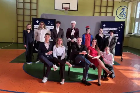 Uczniowie w strojach teatralnych, przygotowujący piosenkę absolwenta.
