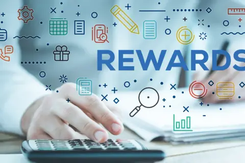 System sugestii pracowniczych. Ręce na kalkulatorze, słowo REWARDS i ikony symbolizujące pracę i nagrody.
