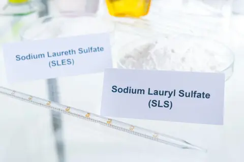 Białe proszki w naczyniach laboratoryjnych, jeden z etykietą "Sodium Laureth Sulfate (SLES)", drugi "Sodium Lauryl Sulfate (SLS)". To właśnie sls co to za substancja?