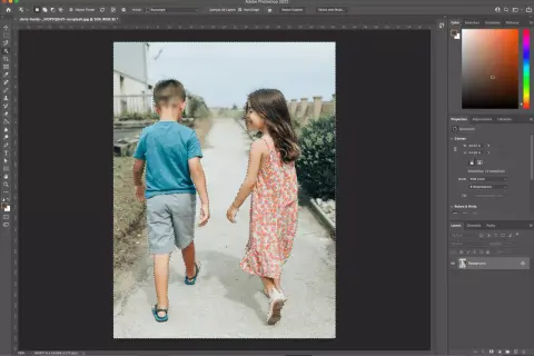 Two children, a boy and a girl, are walking away from the camera. The image is being edited in Photoshop, with a selection tool active, indicating a cut out process.