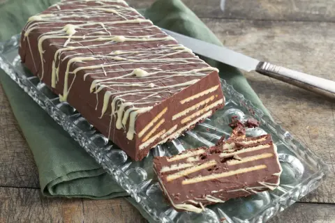 Schokoladenkuchen mit Keksen, ein leckeres rezept kalter hund ohne kokosfett, verziert mit weißer Schokolade.