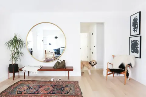Ingresso luminoso con specchio rotondo, un cane curioso e un tappeto persiano. Trucchi per allargare una stanza con illusioni ottiche.