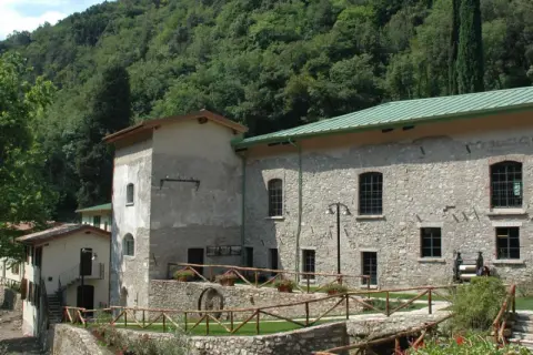 Antica cartiera toscolano immersa nel verde, con un ruscello che scorre e un antico mulino a vista.