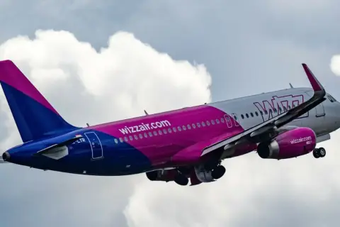 Samolot Wizzair wznosi się na tle chmur. To tanie linie lotnicze, które oferują loty po Europie.