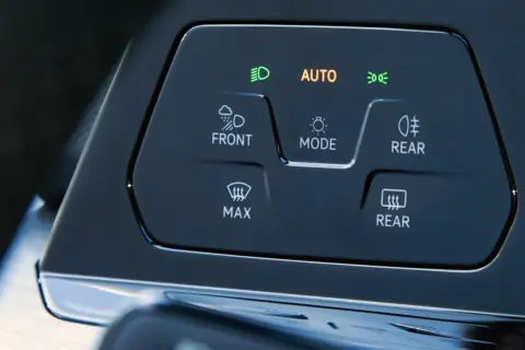 Panel sterowania samochodu z przyciskami: AUTO, FRONT, REAR, MAX. Dowiedz się, jak włączyć światła przeciwmgielne.