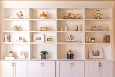 A beautifully styled built-in shelving unit showcases decorative objects, books, and framed photos.