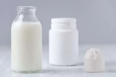 Bottiglia di latte, contenitore bianco e misurino con polvere. Le proteine del latte si trovano in questi prodotti.