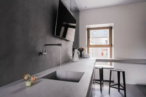 Encimera de cocina moderna con fregadero integrado de microcemento. Grifo cromado y tres manzanas sobre la superficie.