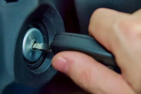 Main d'une personne insérant une clé dans le Neiman d'une voiture. Le prix du changement de Neiman est une préoccupation courante.