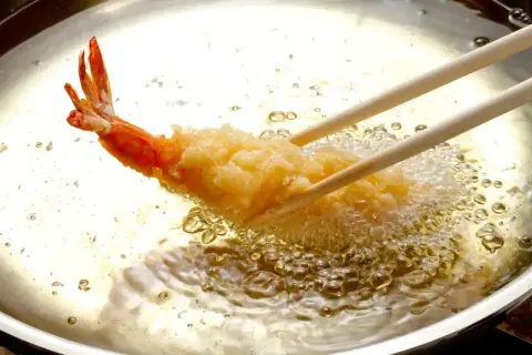 Krewetka w chrupiącej panierce panko smaży się w gorącym oleju.