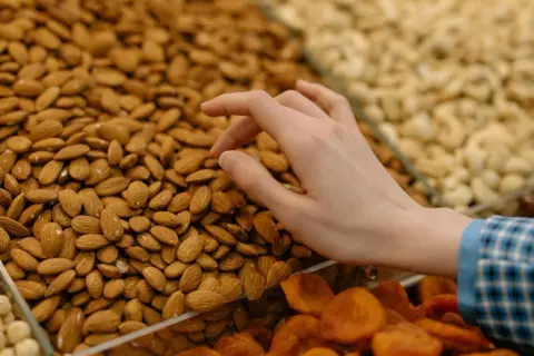 Mano seleccionando almendras para aprender como hacer harina de almendras. Se ven secas y listas para moler.